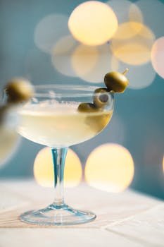 A stylish martini cocktail garnished with olives against a beautiful bokeh background, capturing a sense of elegance and celebration.